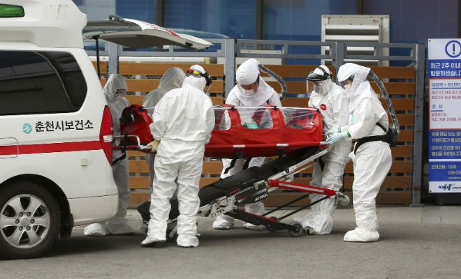 Médicos e enfermeiros cuidam do transporte de um paciente infectado com o novo coronavírus em Chuncheon, na Coreia do Sul — Foto: Lee Sang-hak/Yonhap via AP