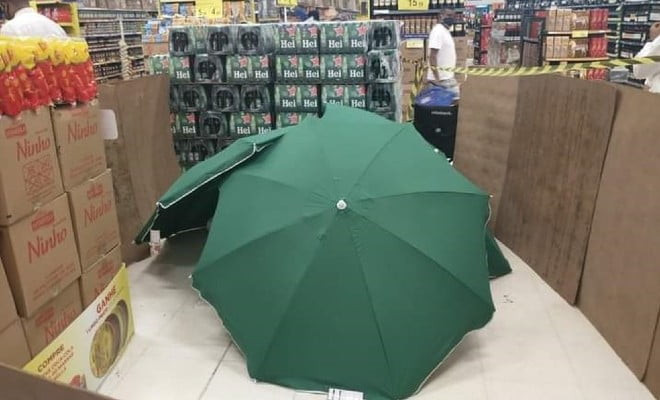 Corpo de representante de vendas que morreu enquanto trabalhava em supermercado no Recife foi coberto com guarda-sóis e isolado por caixas e tapumes improvisados — Foto: Renato Barbosa/WhatsApp 
