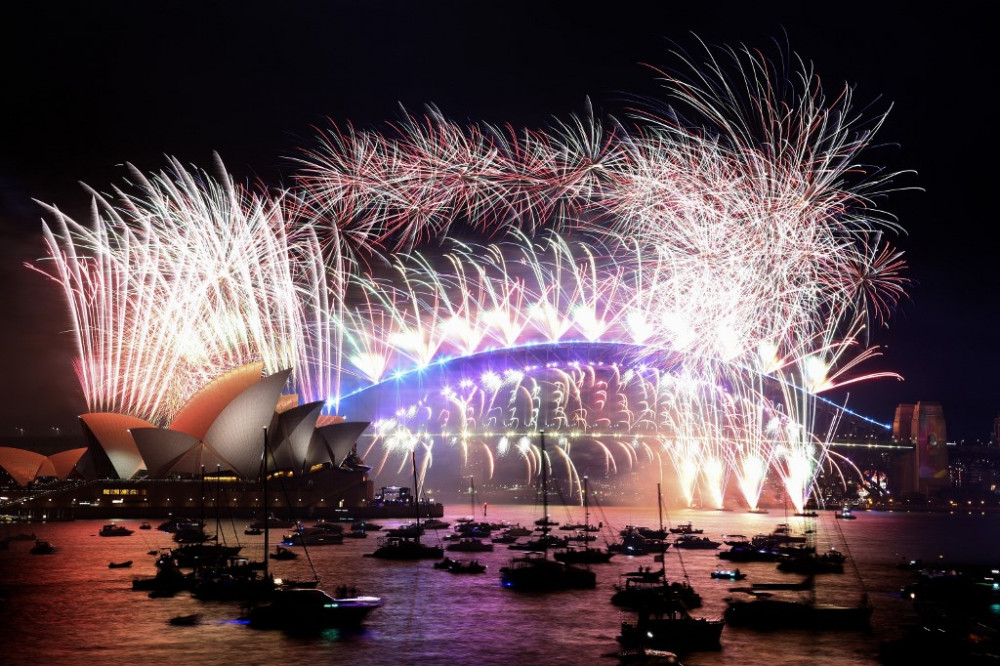 New Year's Eve fireworks light up the sky over Sydney's iconic Harbour Bridge and Opera House (L) during the fireworks show on January 1, 2022. (Photo by DAVID GRAY / AFP)
